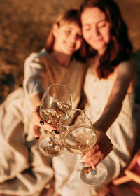 Happy smiling people holding glasses drink wine on the beach at sunset
