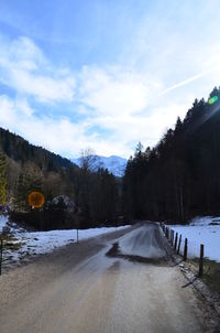 Road amidst trees against sky during winter