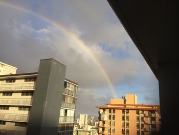 Low angle view of rainbow over buildings against sky