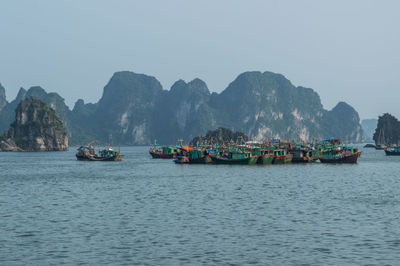 Boats in sea against mountains