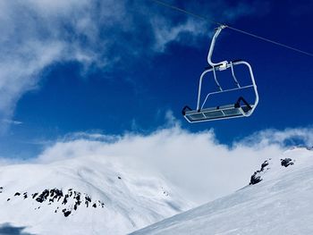 Low angle view of ski lift over snowcapped mountain against sky
