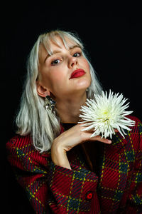 Portrait of young woman against black background