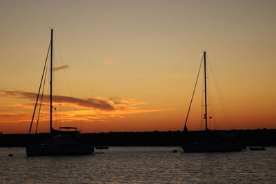 Sailboats sailing in sea against sky during sunset