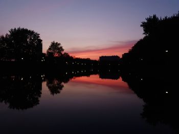 Silhouette trees by lake against sky during sunset