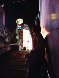 Rear view of man standing on steps at night