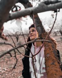 Portrait of young man standing against tree