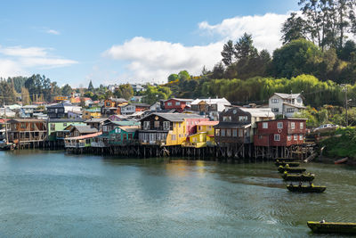 Houses by river against sky