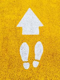 Directly above shot of yellow arrow sign on road