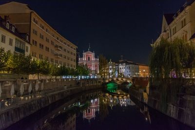Bridge over canal amidst buildings in city at night