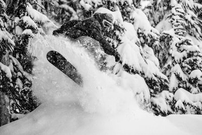 Solo male preforming a jump while snowboarding 