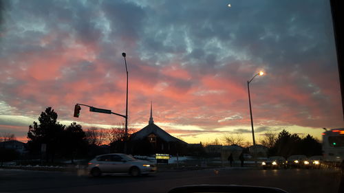 Cars moving on road against cloudy sky