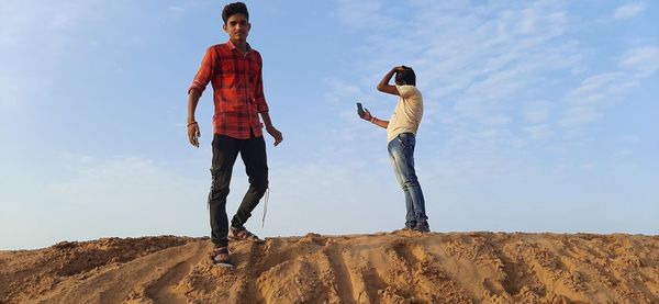 Man and woman standing on rock against sky