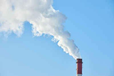 Low angle view of smoke emitting from chimney against sky