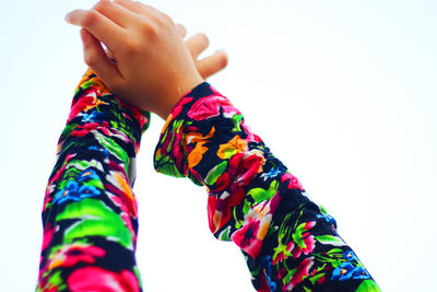 Close-up of boy wearing multi colored hands against sky
