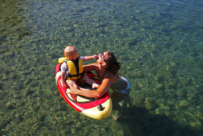 High angle view of mother with child on paddleboard in sea
