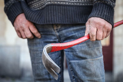 Midsection of man holding crowbar outdoors