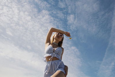 Low section of young woman standing against sky