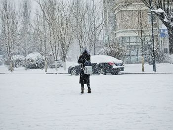 Rear view of man walking on snow covered field