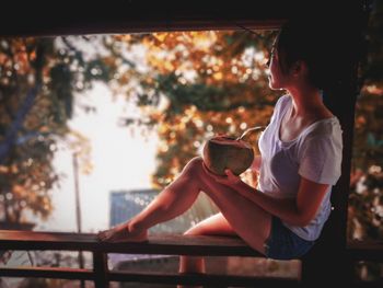 Side view of woman sitting on railing