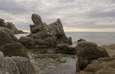 Rock formation on sea shore against sky