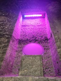 Close-up of illuminated pink light on purple wall