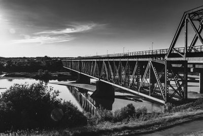 Bridge over river in city against sky