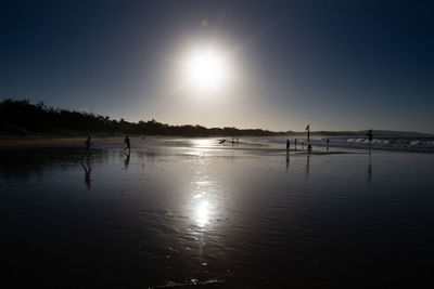 Silhouette people on beach against sky