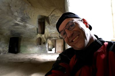 Portrait of man wearing hat standing against wall