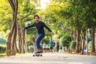 Asian cheerful man playing surfskate or skate board in outdoor park when sunrise time