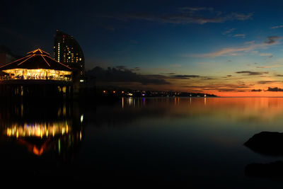 Illuminated bridge over river against sky at sunset