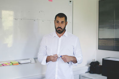 Mature businessman standing against whiteboard while giving presentation in creative office