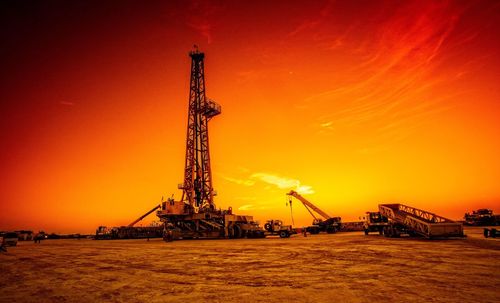 Silhouette cranes against sky during sunset