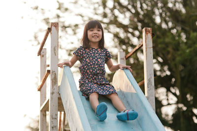 Portrait of girl sliding down on slide in park