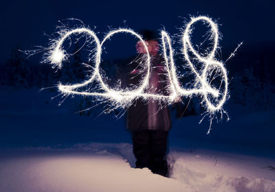 Woman with number fireworks against sky at night