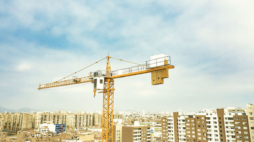 Cranes at construction site against sky in city