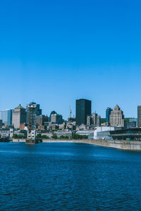 Sea by buildings against clear blue sky