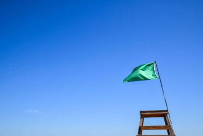 Green flag and lake lifeguard stand