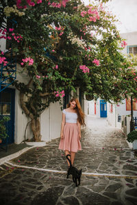 Full length of woman standing by flowering tree