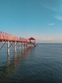 Pier over sea against clear blue sky