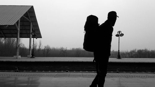 Silhouette backpacker standing at railroad station platform