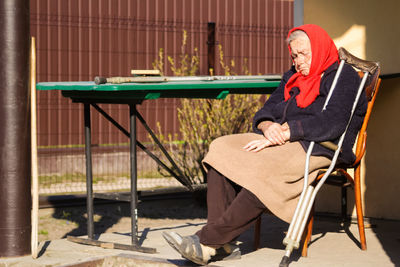 Ukrainian elderly woman in red shawl sleeping outside. 90 years old. alone person. sick and homecare