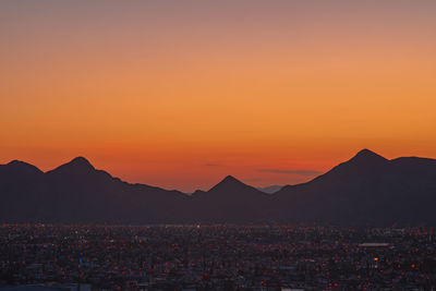 Scenic view of silhouette mountains against orange sky