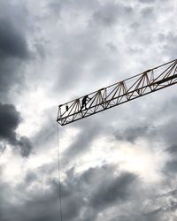 Low angle view of silhouette crane against sky