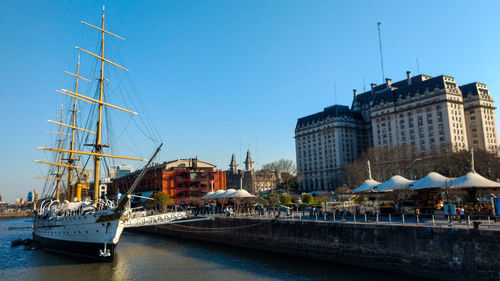 Sailboats moored at harbor against buildings in city