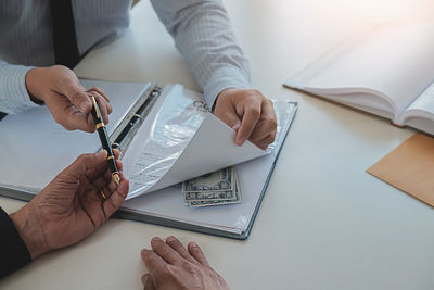 Midsection of man holding paper at table