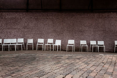 Empty chairs against wall in city