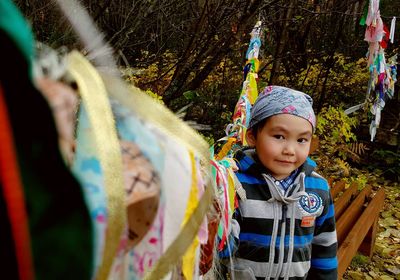 Portrait of boy standing by colorful prayer flags on field