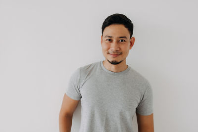 Portrait of young man standing against white background