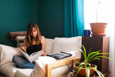 Young woman sitting on sofa at home