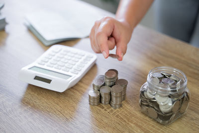 Cropped hand of woman using calculator on table